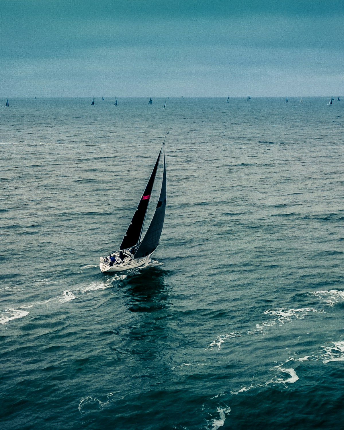A racing yacht cutting through open ocean ahead of the fleet — the mastery that training builds